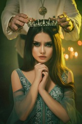 Fantasy medieval couple. Image of lovers - king and queen. hands of man put gothic crown on girl's head. Coronation of woman. vintage costume clothing. Portrait close up girl princess beauty face