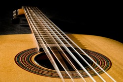 Classical guitar with vibrating strings on a black background