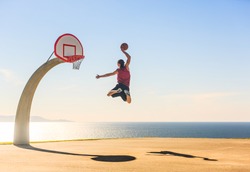 Basketball Player scoring an amazing slam dunk outdoors.