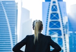 Business challenge. Confident businesswoman overlooking the city center high-rises.