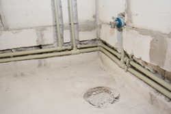 A close-up on a bathroom plumbing system, including network of water supply pipes, drain pipes and toilet closet flange of a drain waste vent concealed autoclaved aerated concrete block wall.