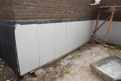 Foundation and basement thermal polystyrene insulation: Rigid eps foam  boards are installed before applying waterproofing membrane to insulate the exterior foundation wall of a new house. 