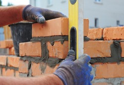 Bricklayer Using a Spirit  Level to Check New  Red Brick Wall Outdoor. Bricklaying Basics Masonry Techniques.