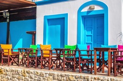 View on typical Greek modern blue and white restaurant with colorful chairs and tables, Greece