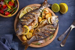 Roasted fish and potatoes, served on wooden tray. overhead, horizontal - image