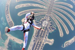 Dubai.People lies on beach Dubai Palm in free fall sky jump. Sea outdoor skydiving travel man. Free fall extreme action sky man on speed 200km.h. Summer fly beach sky man advertising business.