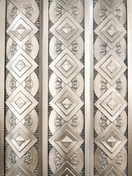 Vertical rows of repeating circle shapes, flower petals, and diamond-oriented squares decorate an exterior wall. The architectural style appears to be art deco, perhaps by casting or relief.