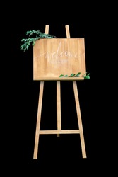Wooden easel with a board. On the board written white paint - Welcome. Isolation on a black background
