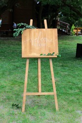 Wooden easel with a board. On the board written white paint - Welcome