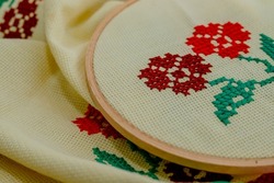 Woman doing cross-stitch with red floral patterns. Cross-stitch art. Hand Mader. Etamine. Cross-stitch painting.