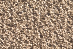 Small ripples and waves in sea on water above sand and bottom. Natural texture, background, surface with copy space.