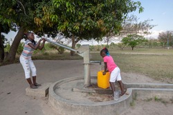  Young girls getting fresh water in the community hand water pump in rural Africa
