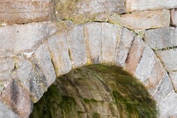Ancient antique stone arch with green rotting lichen close up. Medieval European architecture detail