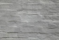 Grey wall, texture, background. The building wall, painted with whiting. Wavy and bumpy surface. Gray brick wall in gray old-style color. Uneven brickwork. Rough whitewashed wall surface