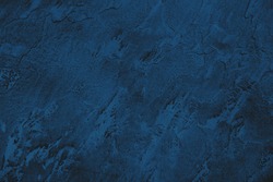 Dark blue colored low contrast stone textured background with roughness and irregularities to your design or product. Color trend concept.