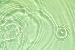Closeup of green transparent clear calm water surface texture with splashes and bubbles. Trendy abstract summer nature background. Mint colored waves in sunlight. Copy space.