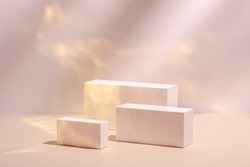 Abstract surreal scene - empty stage with three rectangle white podiums on pastel pink and gold colored background. Pedestal for cosmetic product packaging mockups display presentation