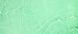 Abstract summer banner background Transparent green clear water surface texture with ripples and splashes. Water wave in sunlight, copy space, top view Cosmetics moisturizer micellar toner emulsion