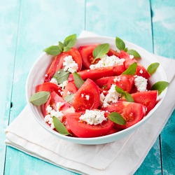 Tomato salad with basil, cheese, olive oil and garlic dressing Blue wooden background 