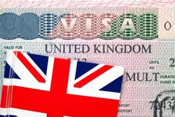 Close-up of United Kingdom visa in passport with Flag of the UK, conceptual political picture