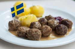 Meatballs with boiled potatoes and sweet red sauce decorated by Swedish flag - traditional Swedish dish