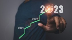 Business target and goal on new year 2023. Man pressing 2023 virtual screen with arrow up. Start up business in the future.