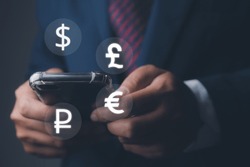 Global currency exchange and forex. Businessman using mobile phone with currency icon ( dollar, euro, pound, and ruble). Currency exchange and global currencies concept.