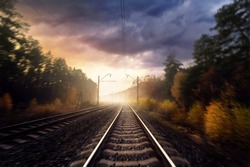 Railroad in the autumn forest. Railway tracks through the forest. Motion blur effect.