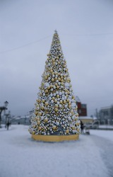 Huge Christmas tree with golden and white decoration in a city square