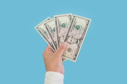 business woman's hand holding dollars isolated on blue background. 5 dollar bills