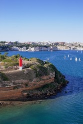 red lighthouse on L'Illa del Rei Hospital Island in the middle of the main navigable entry channel to Mahon in Menorca in the Mediterranean Sea