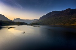 Early morning paddle boarders sail across Crummock Water a lake in the Lake District part of the UNESCO World Heritgae Centre in Cumbria.