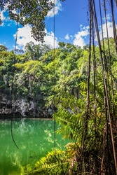 Exit from the water cave in the jungle to a small lake surrounded by mountains. Beautiful tropical nature. Observation platform under the vaults of the cave