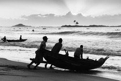 Fisherman pushing their boat, going fishing in the early morning in Madagascar. High quality stock photo and fine art print in Black and white. Photo to hang on the wall