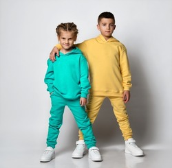 Studio portrait of a cool little boy and girl dressed in stylish bright sports suits with sweatshirts and pants on a white background. Children's sports style concept. Banner.