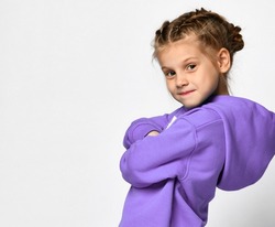 Close up portrait of a cool little girl in a purple hoodie on a white background. Stylish child standing near the free space for text. Concept of children's sportswear and children's style. Banner.