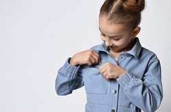 close up photo of a baby girl taking out or hiding something in the breast pocket of her spring cotton jacket.