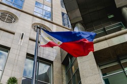 A Philippine Flag waves in the wind in front of a corporate office building in Makati, Philippines.