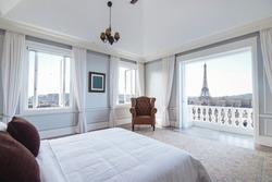 Interior of classic modern bedroom of a hotel or apartment condominium with beautiful views of Paris cityscape.
