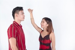 A young woman measuring her friend's height difference with her hand. Sizing up and amazed at how tall he is. Gifted with great genes.