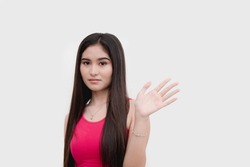 A young uneasy asian woman waving someone off expressing disinterest or apprehensiveness. Isolated on a white backdrop.