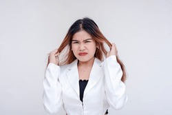 A frustrated and irritated young woman pulling her hair with both hands in annoyance. Clearly agitated and cracking under pressure. Isolated on a white background.