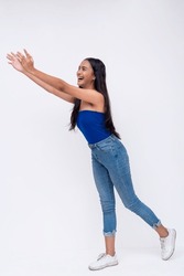 Side view of a young southeast asian woman tries to catch something falling. Reaching out with her arms. Full body photo isolated on a white background.