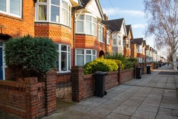 A typical row of English terraced houses with wheelie bins outside on the pavement