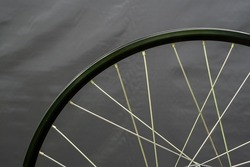 A bicycle wheel without a tire on a black background in the workshop. Bicycle repair. Rim and spokes of a mountain bike wheel close-up.