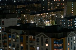 Night panorama of the city. Tall apartment buildings illuminated by night illumination. Top view of windows and roofs of houses