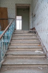 An old staircase in a large house with a wooden railing. Renovation of the mansion. Destroyed houses and rooms after an earthquake or cataclysm. Dirt and ruin in the old house.