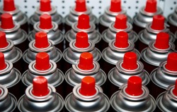 aerosol cans with a bright red lid are in a row. Macro photo. Selective focus on the nozzle. blurred photo