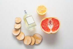 Natural ingredients for a woody citrus fragrance, a bottle of oil or perfume on a background of grapefruit, lemon and wood. The concept of perfumes and aromatherapy, body care, natural oils.