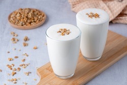 Kefir, buttermilk or yogurt with granola. Yogurt in glass on white wooden background. Probiotic cold fermented dairy drink. Gut health, fermented products, healthy gut flora concept. Copy space.